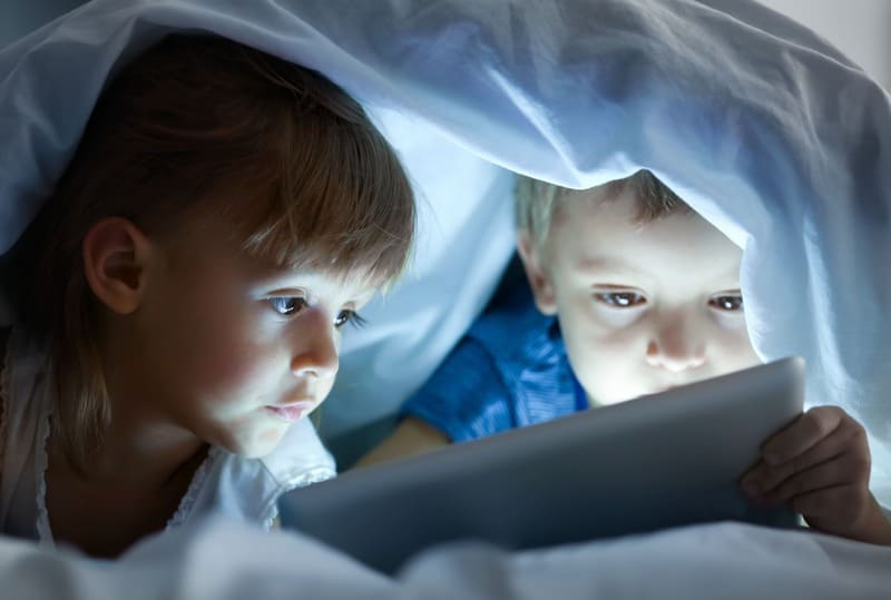 enfants qui regarde leur tablette dans leur lit